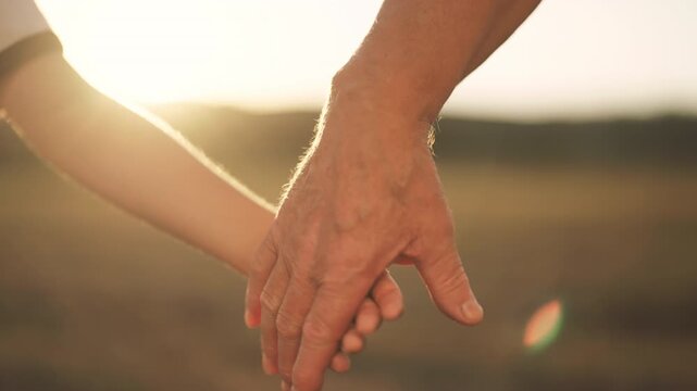 Family ties, closeup view of grandfather and grandson hands, holding in nature. Old man and little boy stretching hands to each other, love and care, continuity of generation, people connection