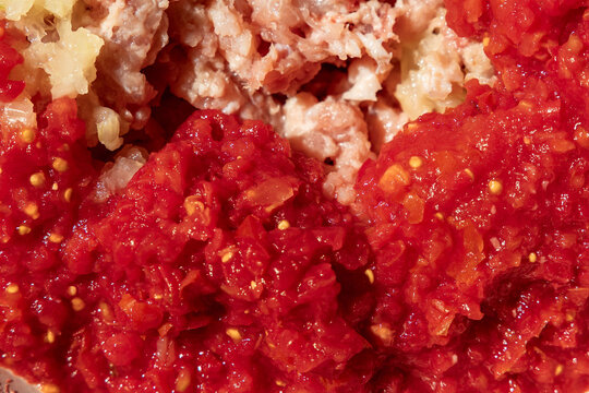 Macro shot of raw minced meat mixed with crushed tomatoes