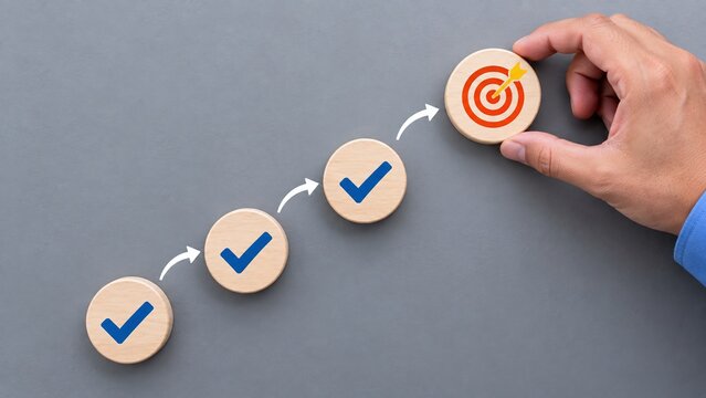 Businessman hand placing target icon on wooden block as final step of business success strategy process workflow and project completion