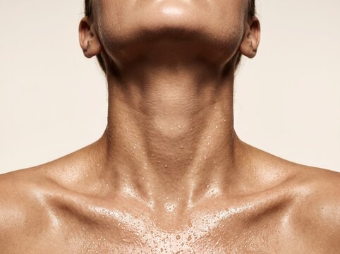 Close-up of a woman's wet neck and collarbone with water droplets on skin