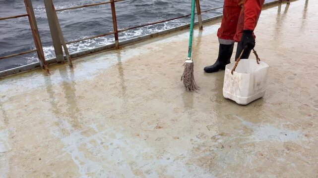 crew member moping cleaning main deck of the ship with chemicals.