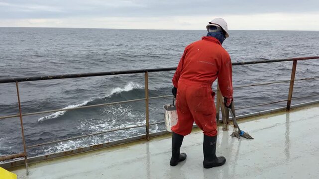 seafarer moping main deck of the ship during the sea passage.