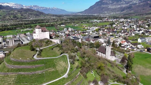 gutenberg castle hilltop round tower parish church terraced vineyard slopes balzers town rooftops rhine valley farmland snowcapped alpine peaks drone footage establishing shot liechtenstein