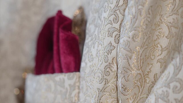 Close up on brocade fabric with ornate pattern and red pocket square