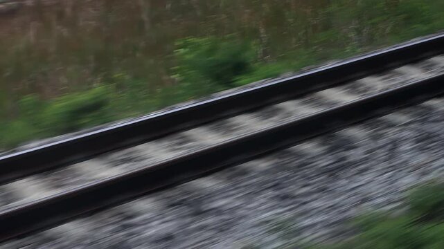 Fast motion blur of railway tracks and green scenery viewed from a moving train window