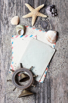 Flat lay composition on a wooden pier featuring seashells, dried flowers, sand, and romantic love letters. Conceptual background for book covers, nostalgia, summer romance, and memories.