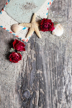 Flat lay composition on a wooden pier featuring seashells, dried flowers, sand, and romantic love letters. Conceptual background for book covers, nostalgia, summer romance, and memories.