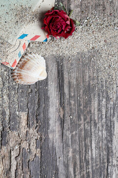 Flat lay composition on a wooden pier featuring seashells, dried flowers, sand, and romantic love letters. Conceptual background for book covers, nostalgia, summer romance, and memories.