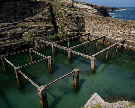 High angle view of the traditional stone and concrete lobster ponds (cet&aacute;reas) filled with clear turquoise sea water in Rinlo, Ribadeo, Galicia, Spain. 