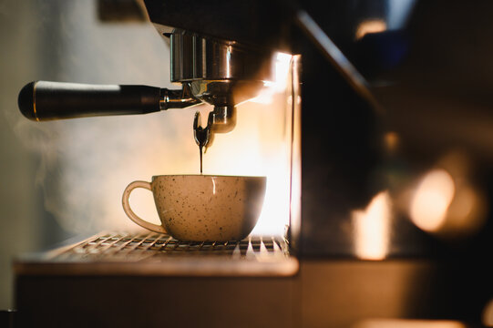 Espresso machine brewing hot coffee into ceramic cup