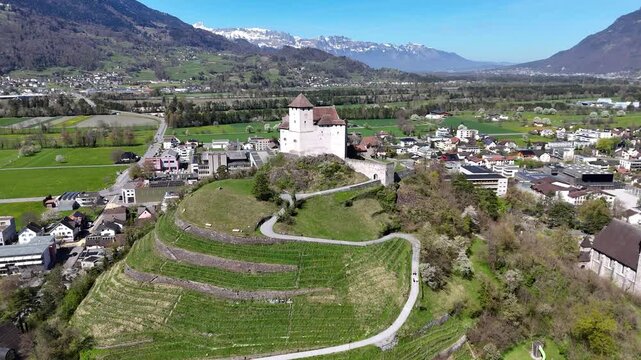 snowcapped alpine peaks mountain range backdrop gutenberg castle hilltop vineyard terraces balzers village rooftops rhine valley farmland aerial orbit drone footage liechtenstein heritage site
