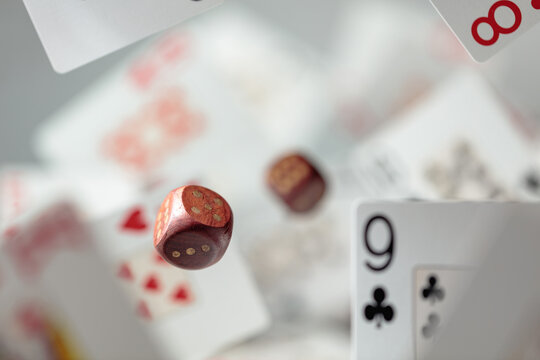 Wooden die in motion surrounded by playing cards.