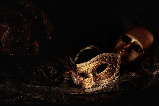 Golden carnival masks on a dark background.
