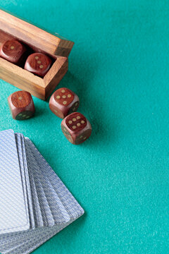 Playing cards and wooden dice on a green cloth.