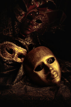 Golden carnival masks on a dark background.