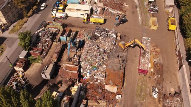 Top down aerial view of a scrap metal yard with excavators sorting and crushing scrap on a sunny day