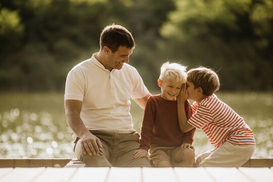 Joyful bonding moment by the lake with a father and his two sons