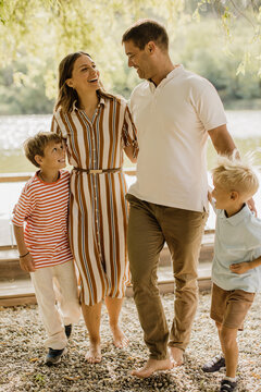 Family enjoying a joyful walk by the serene lakeside on a sunny day