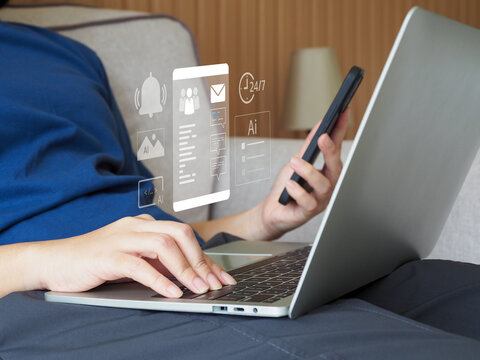 Person typing on laptop and holding smartphone with digital app interface icons floating, remote work scenario, focused productivity and communication