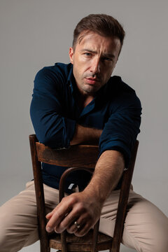 Serious middle aged man leaning on chair looking forward