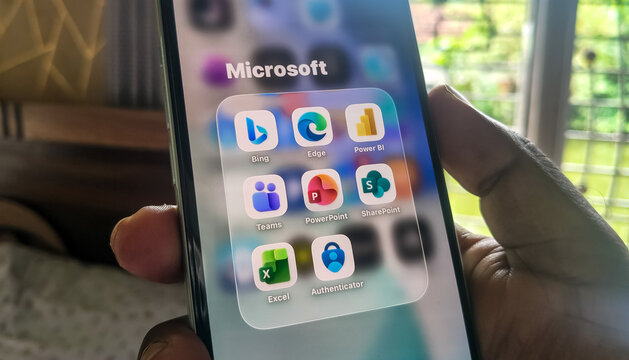 Mobile phone showing folder of Microsoft productivity software applications in hand.