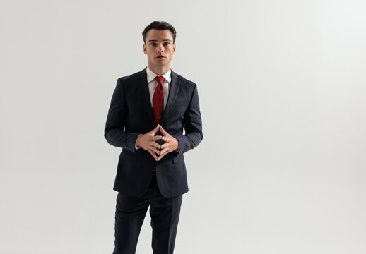 Confident man standing and touching fingers together