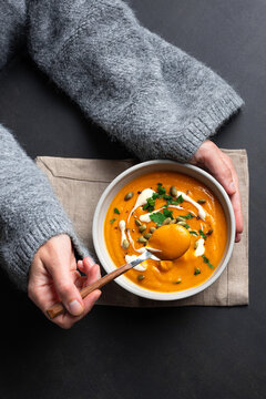 Woman in knitted sweater eating fresh pumpkin soup
