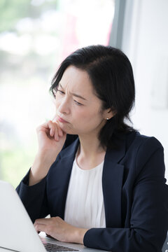パソコンを見ながら仕事のトラブルに悩む女性会社員、オフィスで考え込むビジネスウーマンの仕事のストレスや悩み