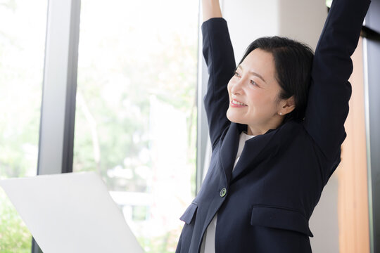 仕事の合間に肩こりのストレッチをする女性会社員、オフィスでリフレッシュするミドル世代のビジネスウーマン 健康経営のイメージ
