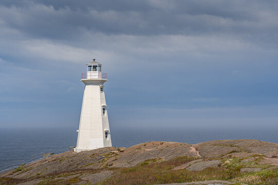 Wei&szlig;er Leuchtturm von Cape Spear auf einer felsigen Klippe am Meer in Neufundland