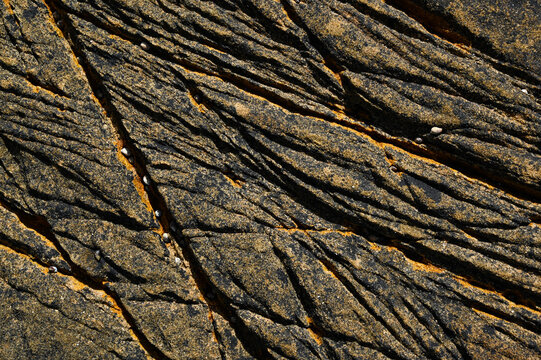 A stone granite rock furrow formation on the Atlantic coast, with grooves and crevices carved out by the waves and seawater, weathered and eroded.