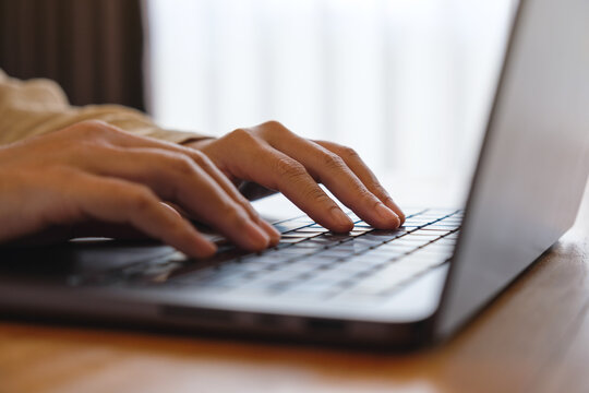 Closeup image of a woman working and typing on laptop computer keyboard