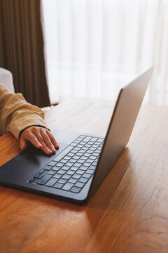 Vertical closeup image of a woman working and touching on laptop computer touchpad