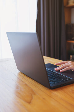 Vertical closeup image of a woman working and touching on laptop computer touchpad