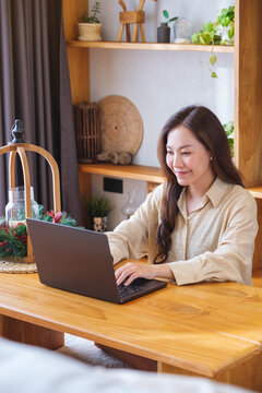 Vertical portrait of a woman using and working on laptop computer at home