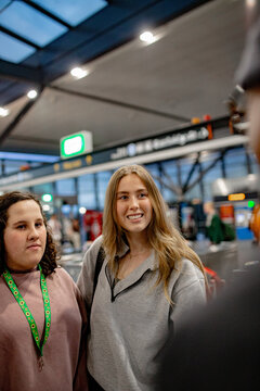 Teen girl and support worker standing together and talking with another commuter