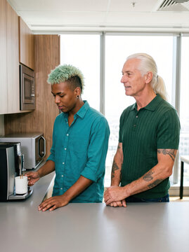 Colleagues waiting for coffee in an office kitchen