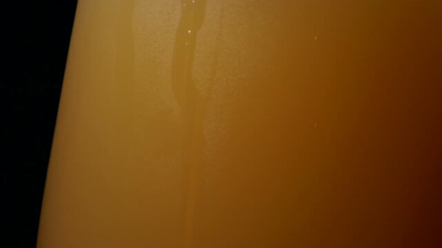A glass of fresh India pale ale craft IPA beer, isolated and rotating against a black background. Side of glass.