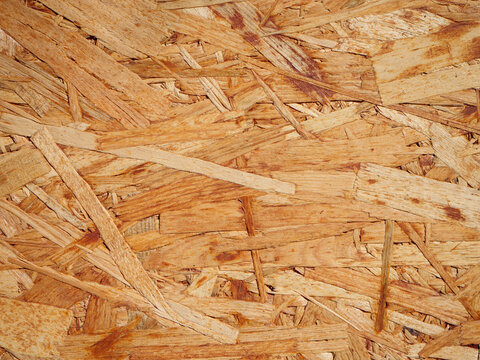 Close-up texture of OSB oriented strand board made from compressed wood strands and chips, creating a natural wooden background for construction, design and material concepts.