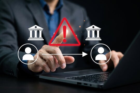 Businessman touching a digital warning icon representing a bank transfer risk