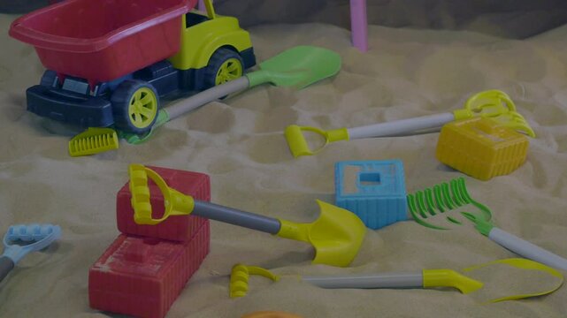 Close up of colorful plastic toys for playing in sandbox with sand and truck