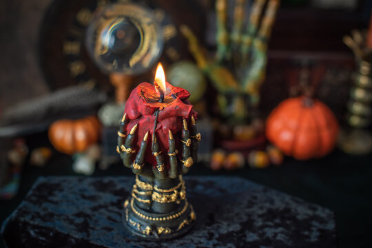 Burning heart candle held by witch hands on magical altar for love spells, cleansing negative energy and romantic rituals 