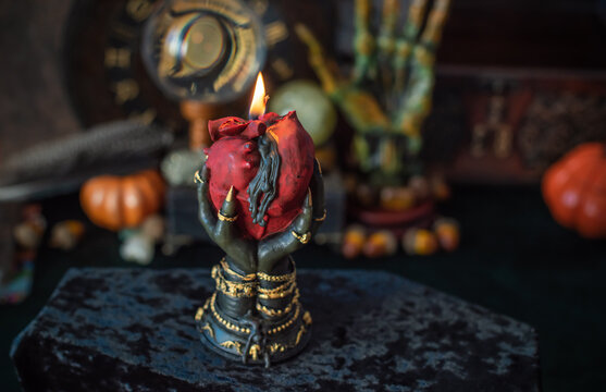 Burning heart candle held by witch hands on magical altar for love spells, cleansing negative energy and romantic rituals 