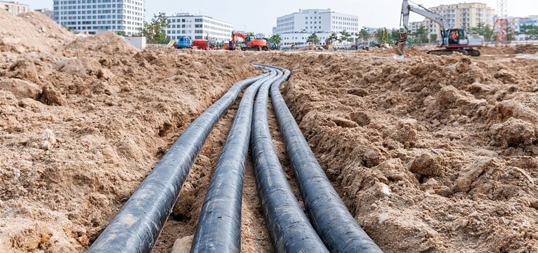 Freshly installed underground water pipes embedded in soil at an active industrial construction site.