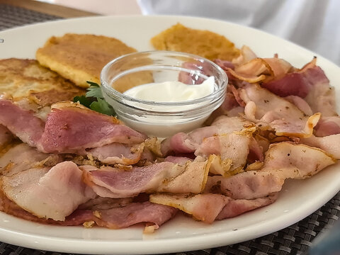 Closeup of crispy bacon and potato pancakes with sour cream dip