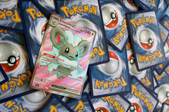 Pok&eacute;mon rare card with holographic finish and Italian text displayed over scattered trading cards. Collectible card game concept for collectors, gaming and TCG enthusiasts.