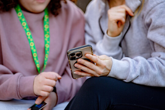 Close-up of young women's hand holding a smartphone while sitting on an urban bench