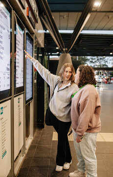 Young support worker woman pointing out information on a digital metro timetable