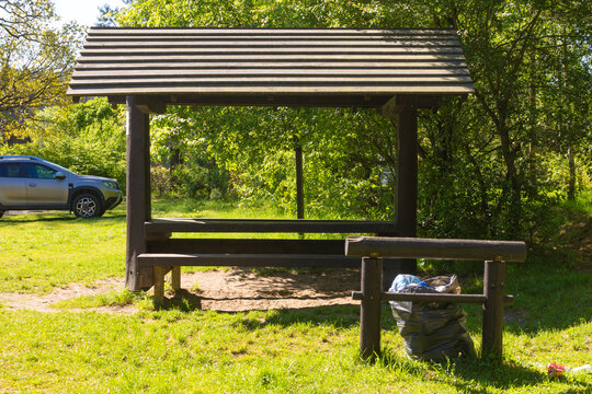 Peaceful outdoor seating area near a forest with a parked vehicle under bright sunlight