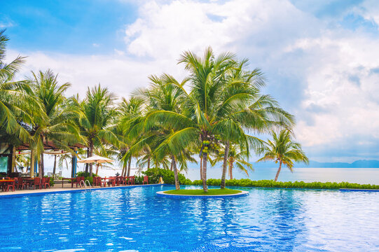 A pool on the beach by the sea in a luxury resort. A pool with palm trees in the tropics in Asia